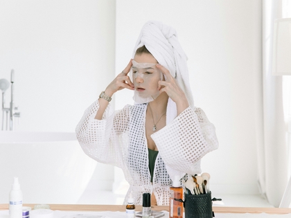 Woman applying Korean skincare products, highlighting natural glow and healthy skin.