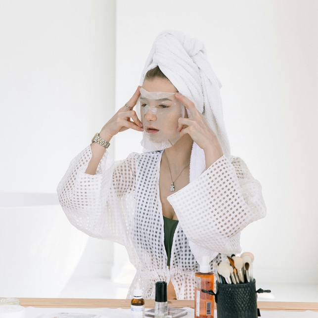 Woman applying Korean skincare products, highlighting natural glow and healthy skin.